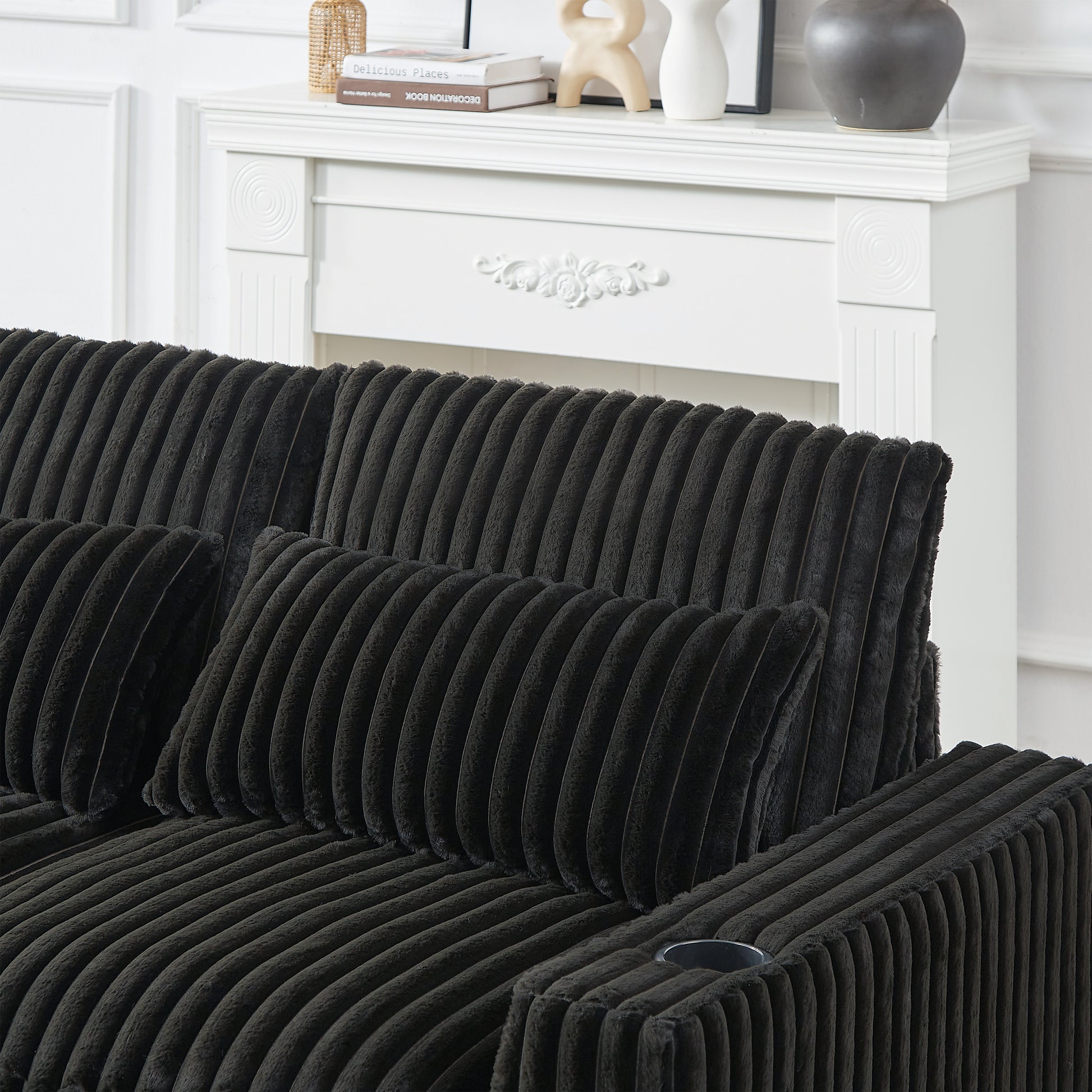 Black corduroy sofa with plush throw pillows and a builtin cup holder