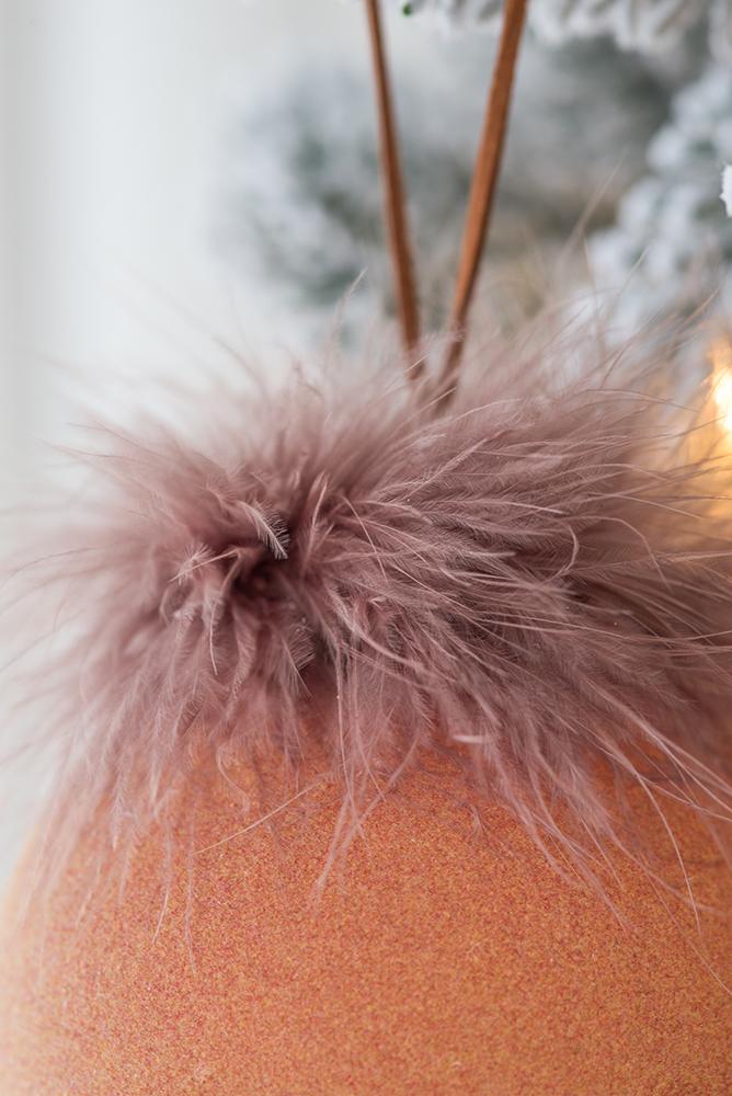 Dusty rose feathered ornament with a textured orange surface