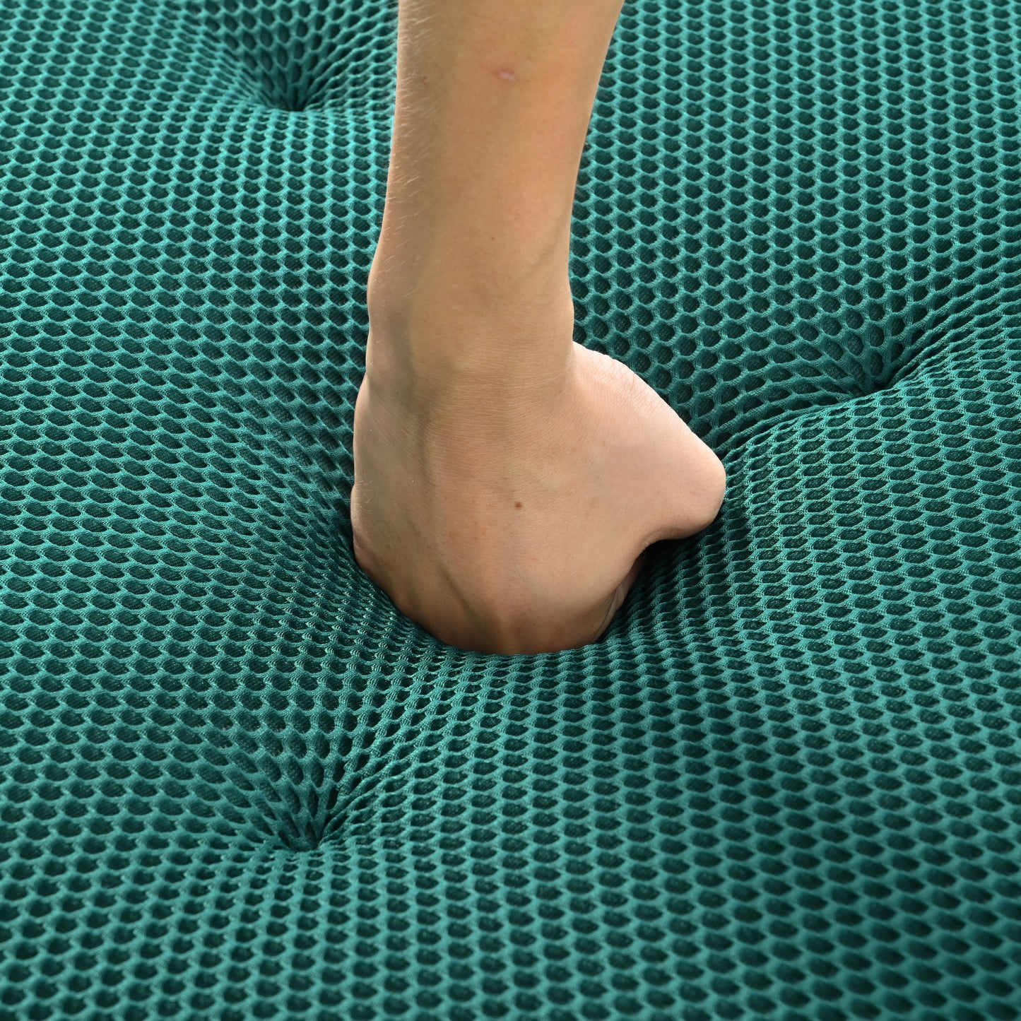 Hand pressing into teal hexagonal mesh fabric highlighting its cushioning properties