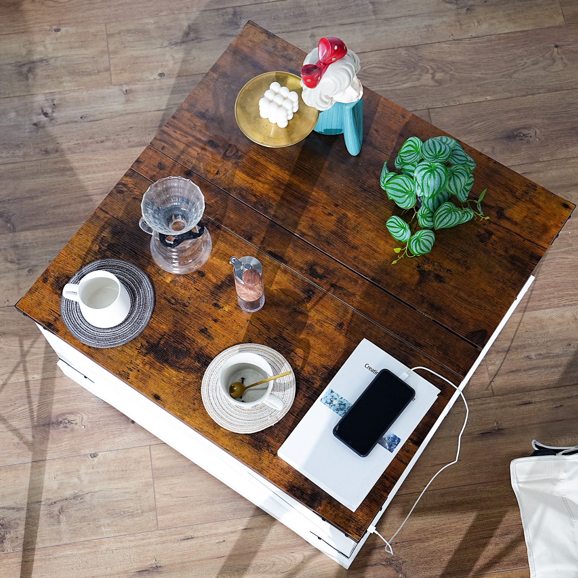 Rustic brown coffee table with white drawers holding a plant cup and phone
