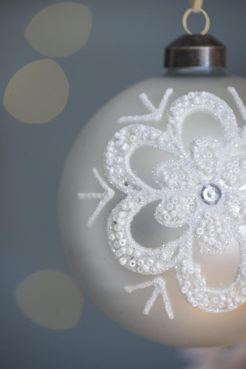 Elegant white glass Christmas ornament with beaded snowflake detail and subtle glitter