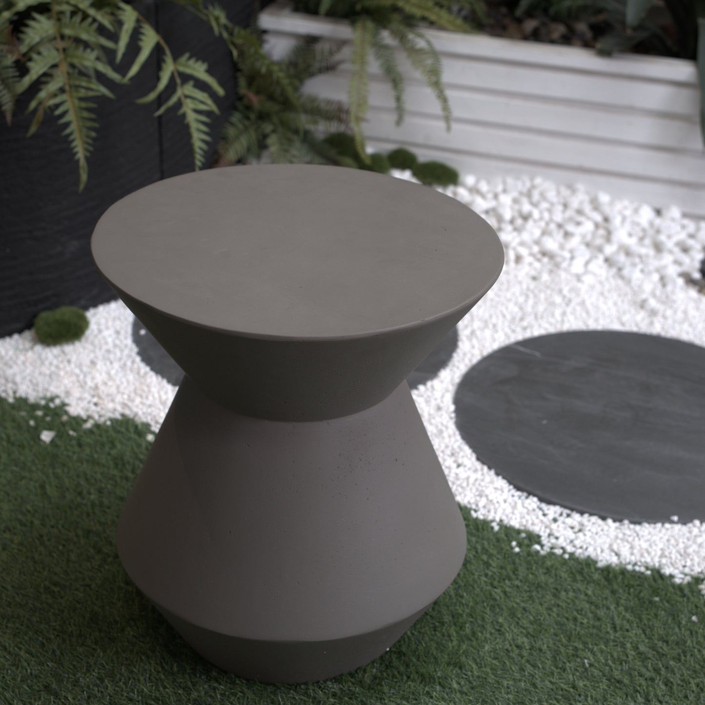 Modern hourglassshaped concrete garden stool in charcoal grey perfect for outdoor spaces