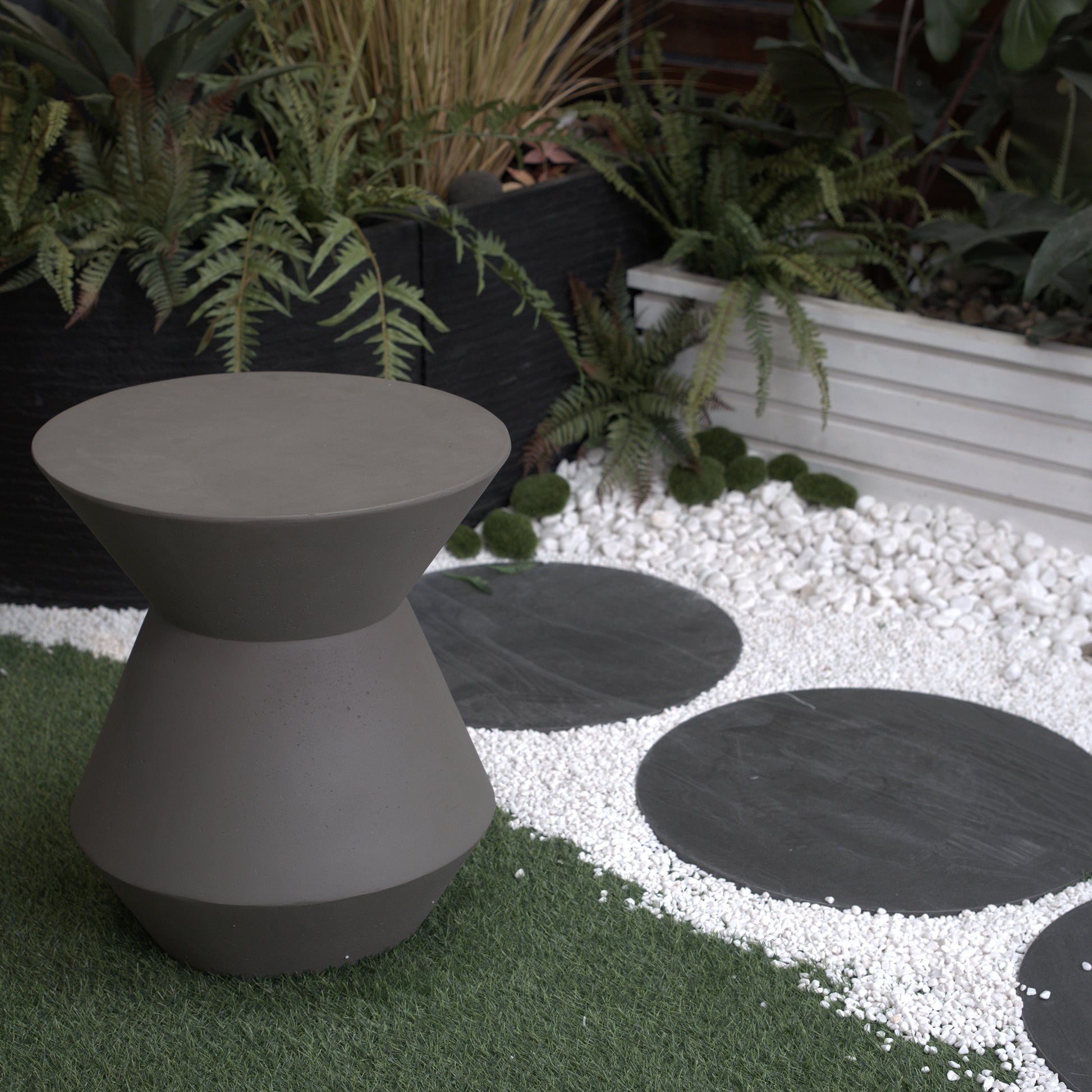 Hourglassshaped charcoal grey concrete side table for outdoor use