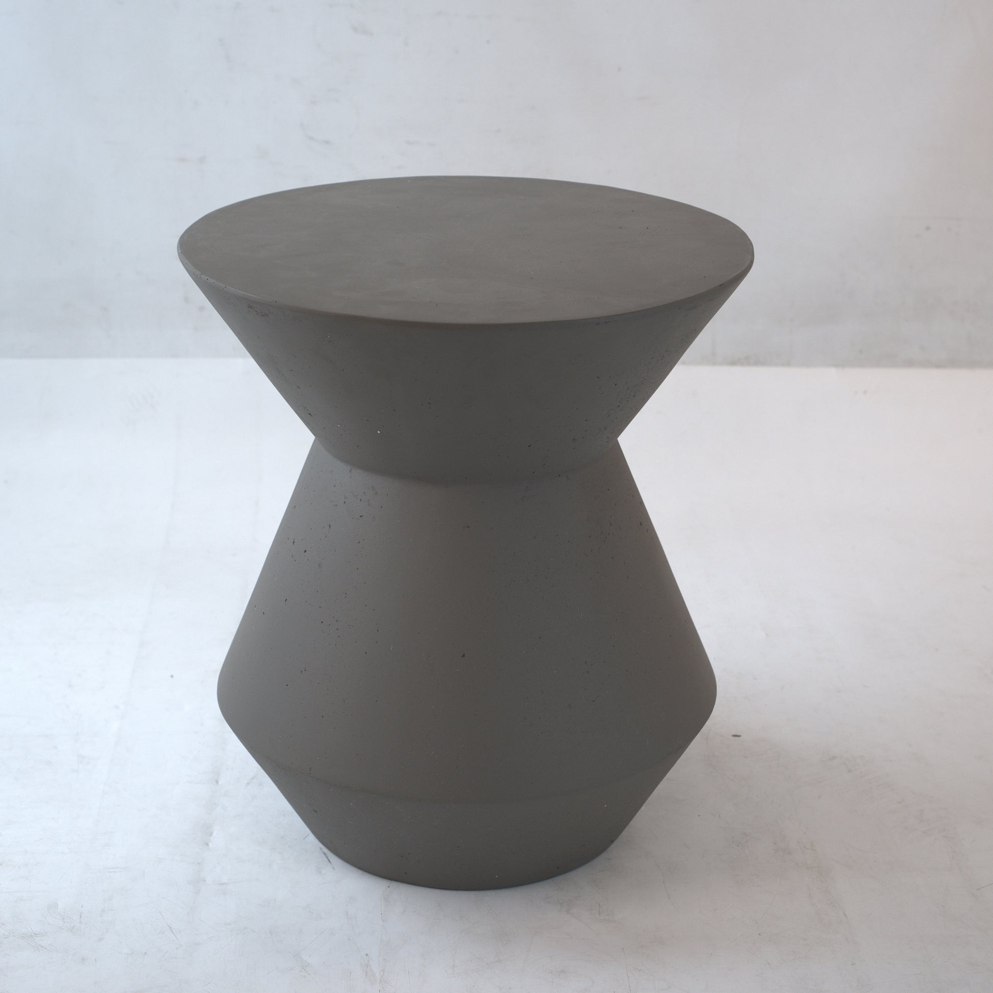 Gray concrete hourglass stool with a smooth matte finish