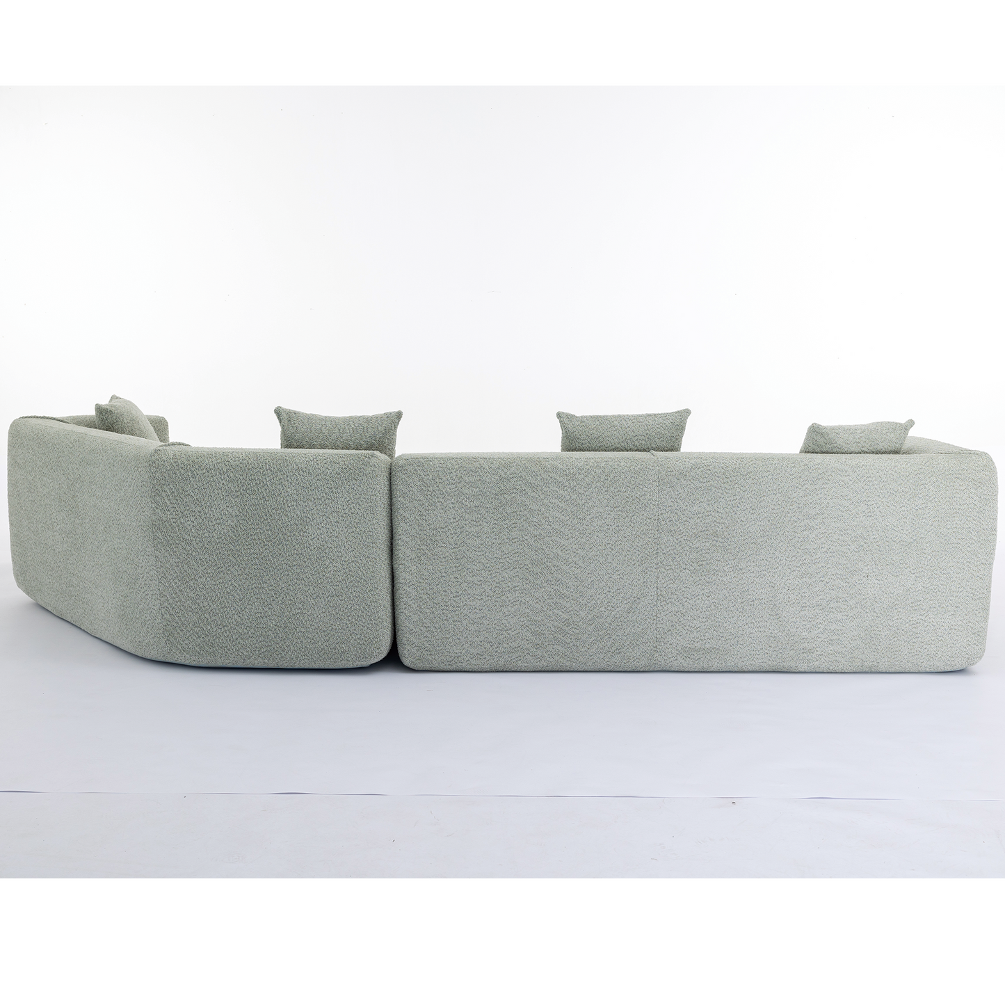 Curved modular sectional sofa in textured light green fabric with throw pillows