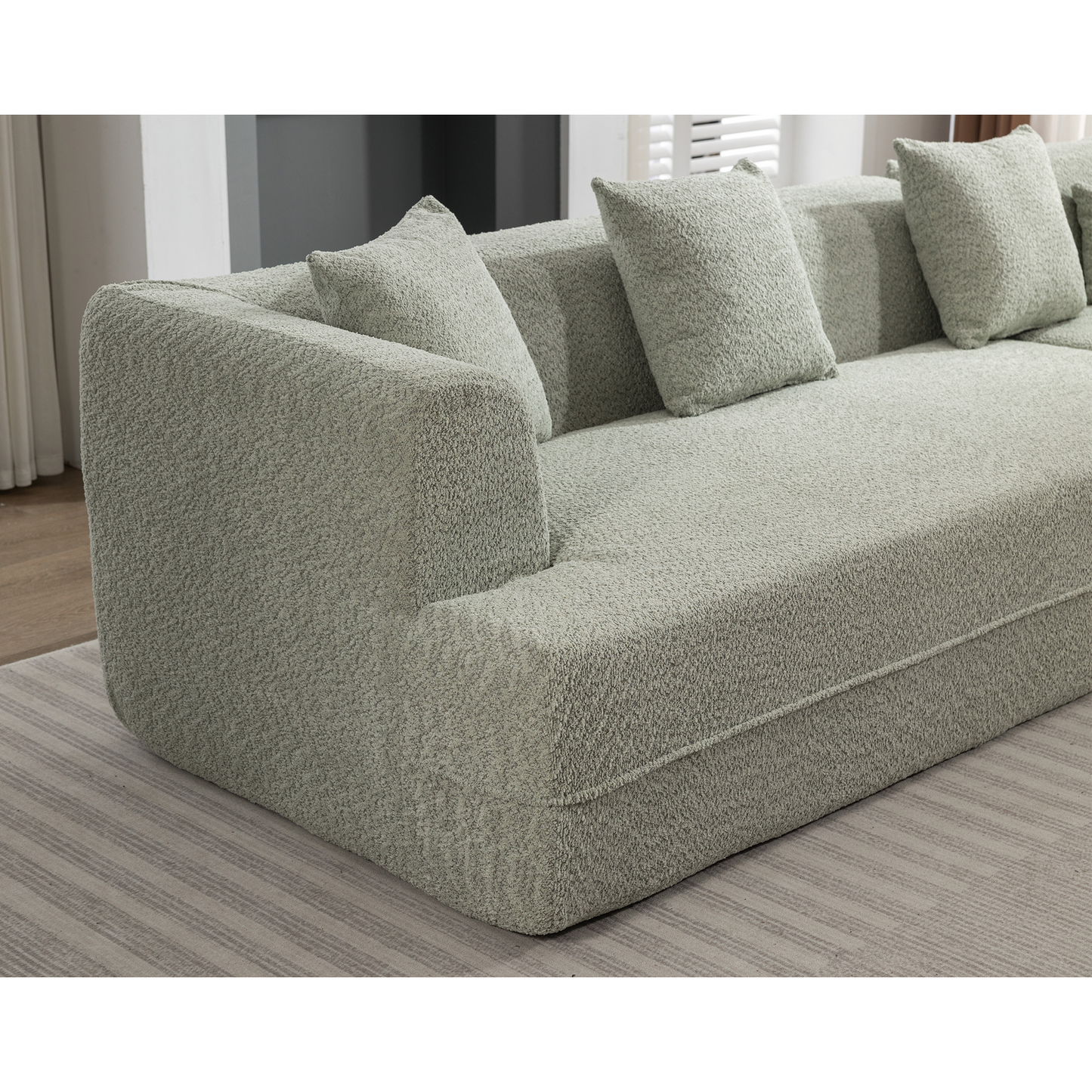 Sage green boucle sectional sofa with plush throw pillows for a cozy living room