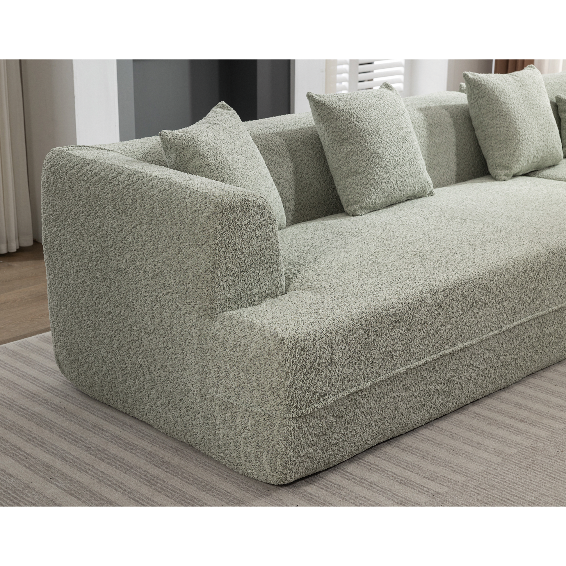 Sage green boucle sectional sofa with plush throw pillows for a cozy living room