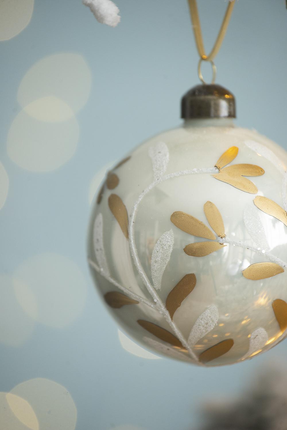 Cream glass Christmas ornament with gold leaf design and glitter accents