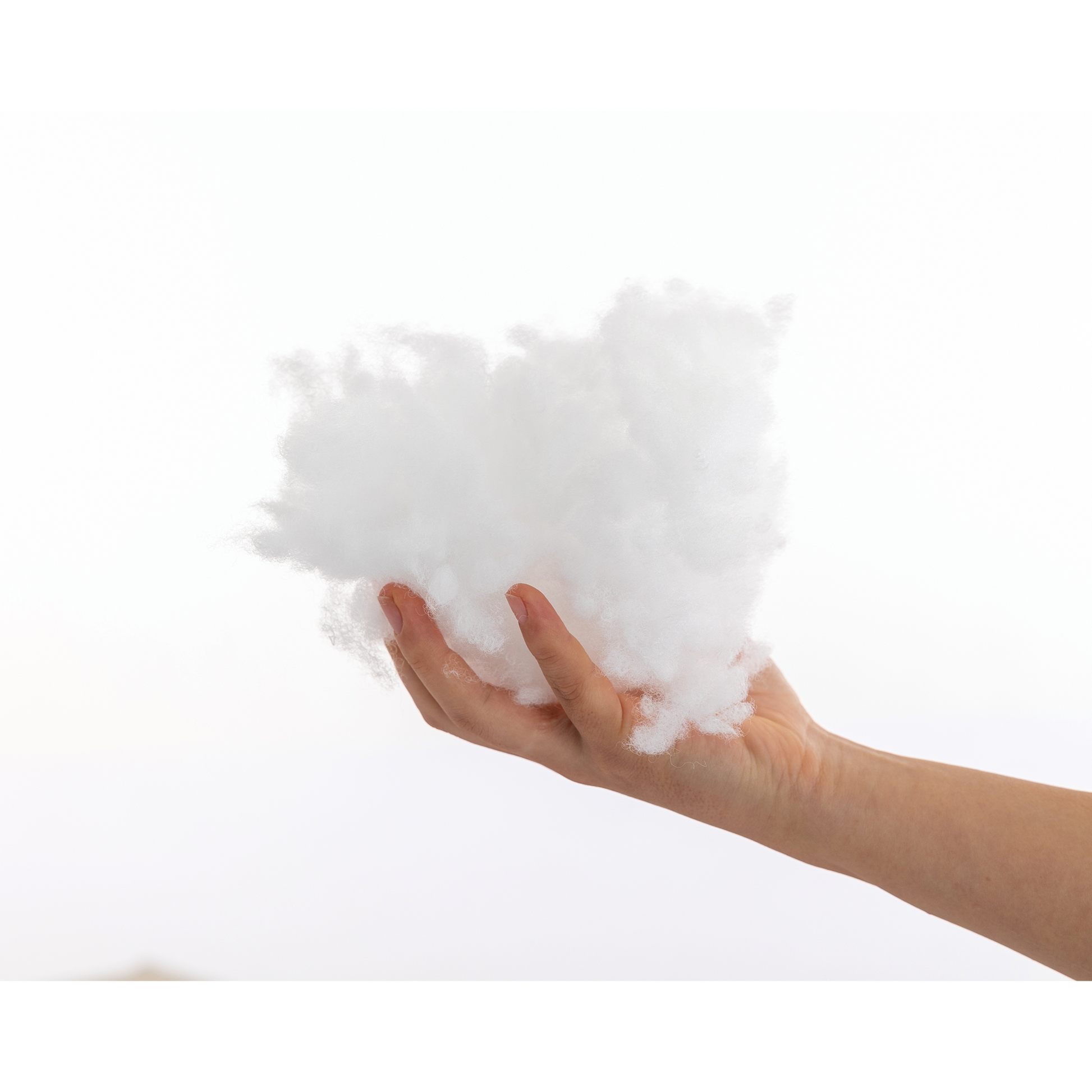 Hand holding fluffy white polyester fiber filling for crafts and pillows