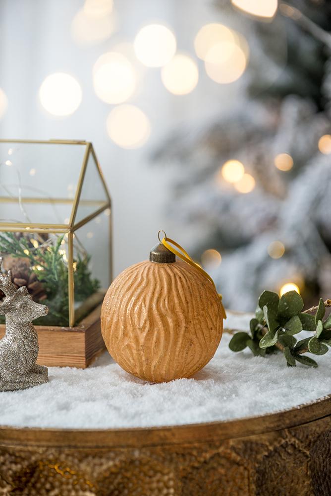 Textured round walnut Christmas ornament with a rustic natural finish and yellow ribbon loop
