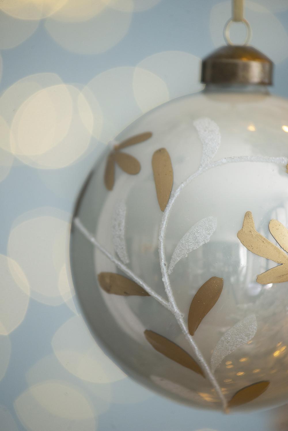 White glass Christmas ornament with gold leaf pattern and glitter accents
