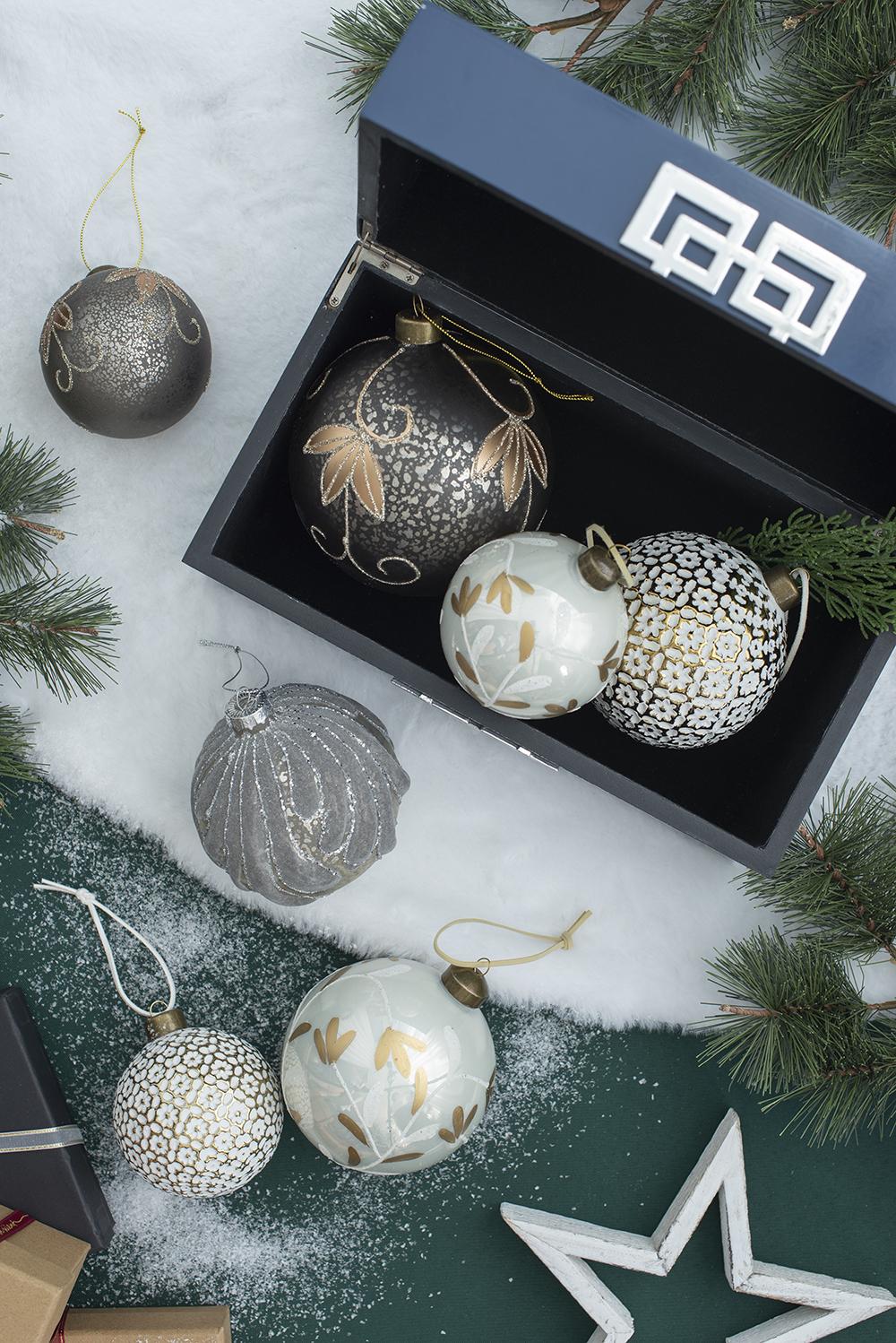 Set of ornate glass Christmas ornaments in black white and grey inside a navy blue box