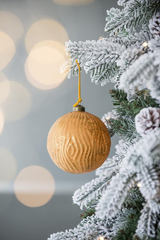 Gold woodgrain Christmas ornament hanging on a frosted tree branch