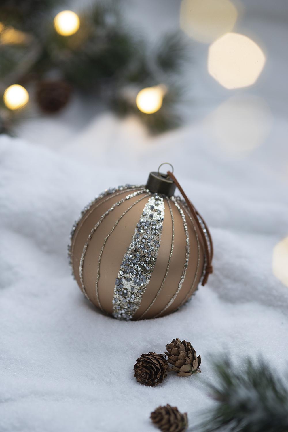 Champagne glitter striped Christmas ornament with twine hanger on snow