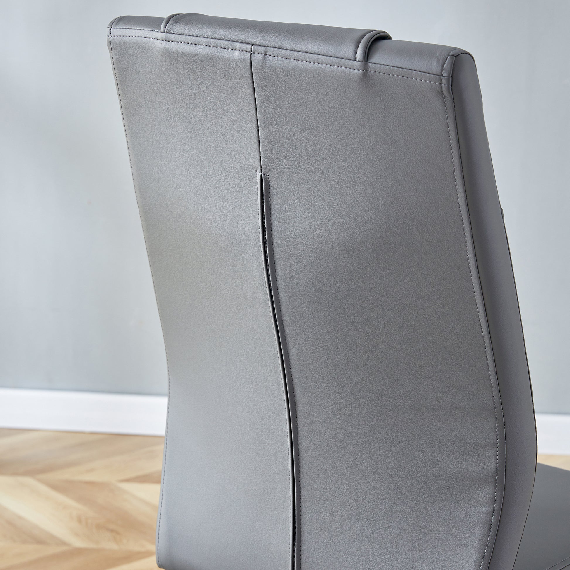 Closeup of a grey faux leather dining chair back with elegant stitching detail