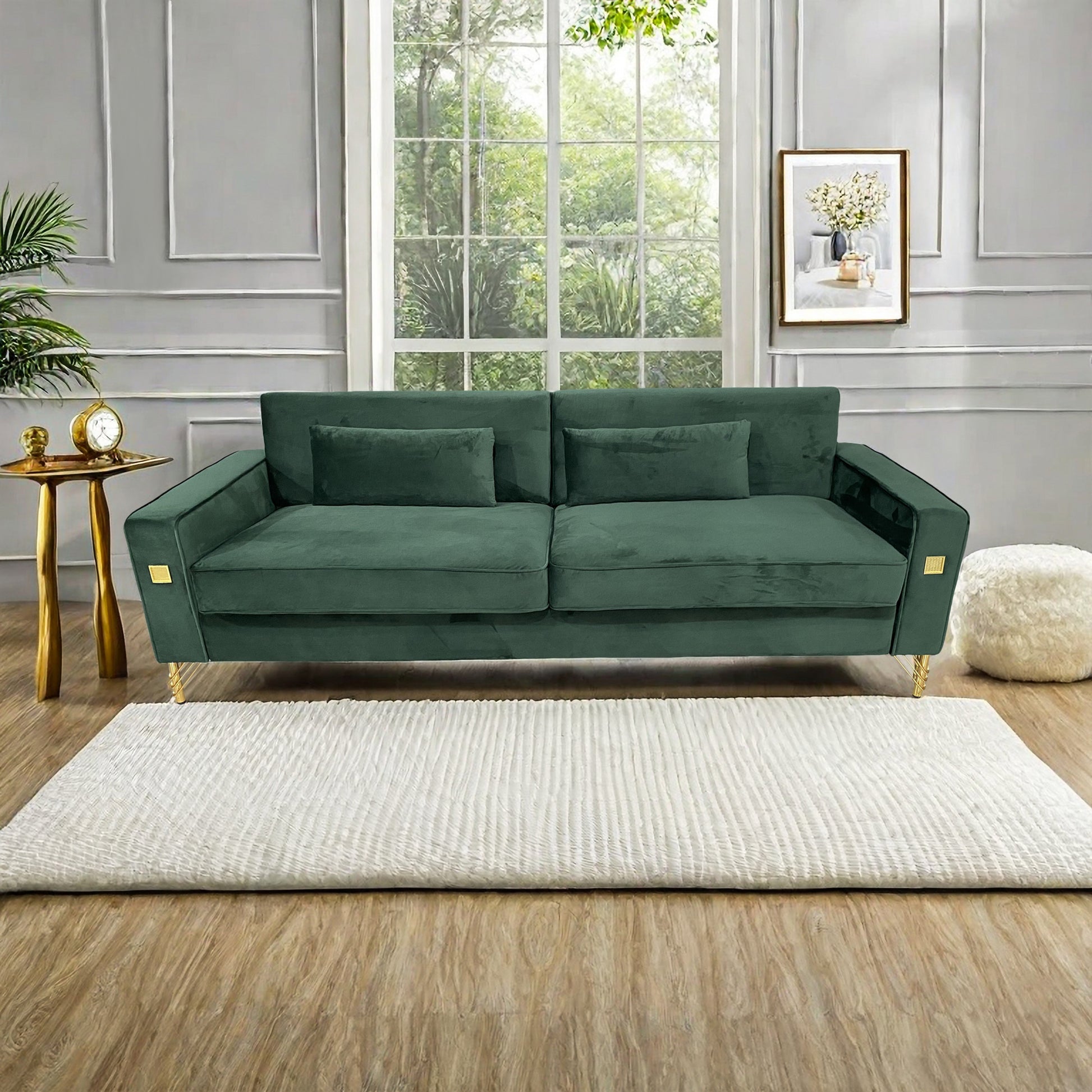 Emerald green velvet sofa with gold accents and two matching throw pillows