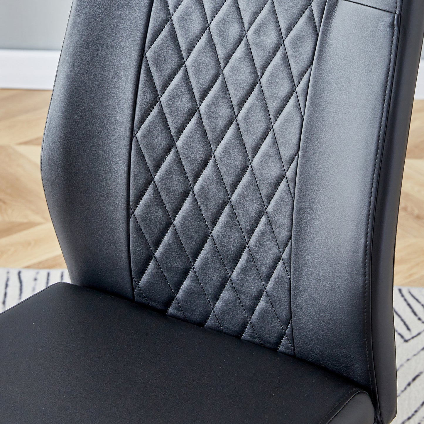 Closeup of a black leather chair with diamondstitched detailing on the seat and backrest