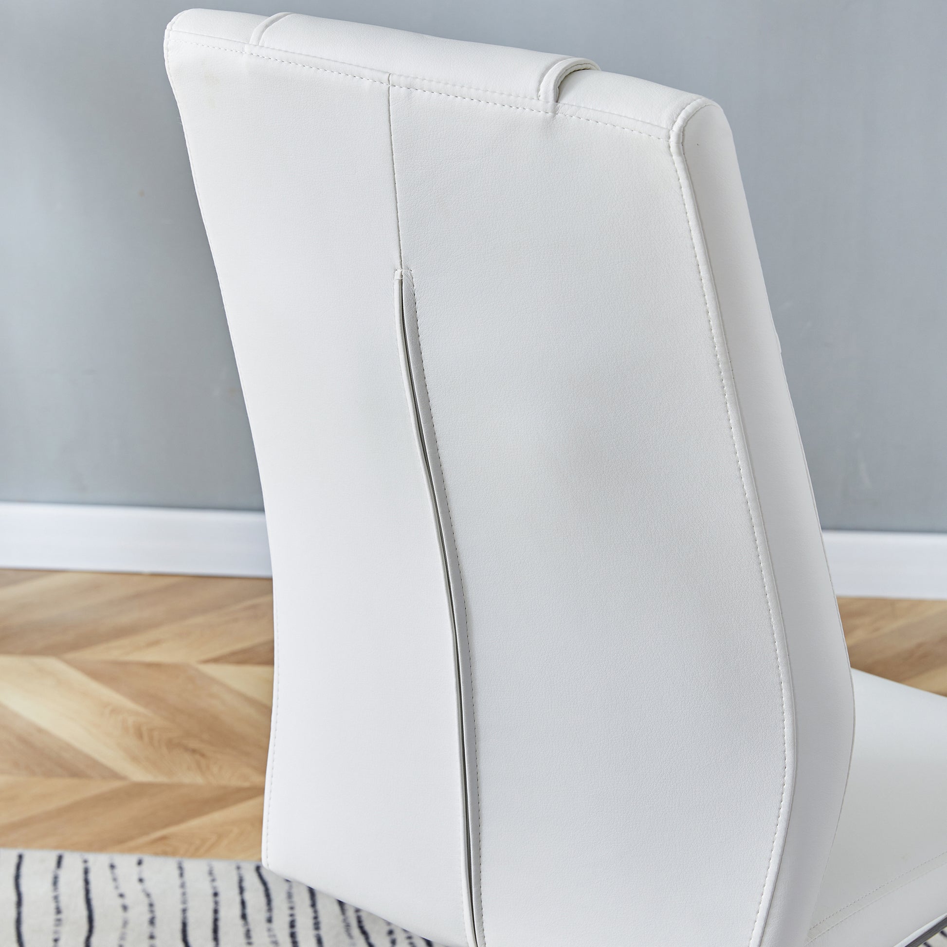 Closeup of a white leather dining chair back with stitched detailing