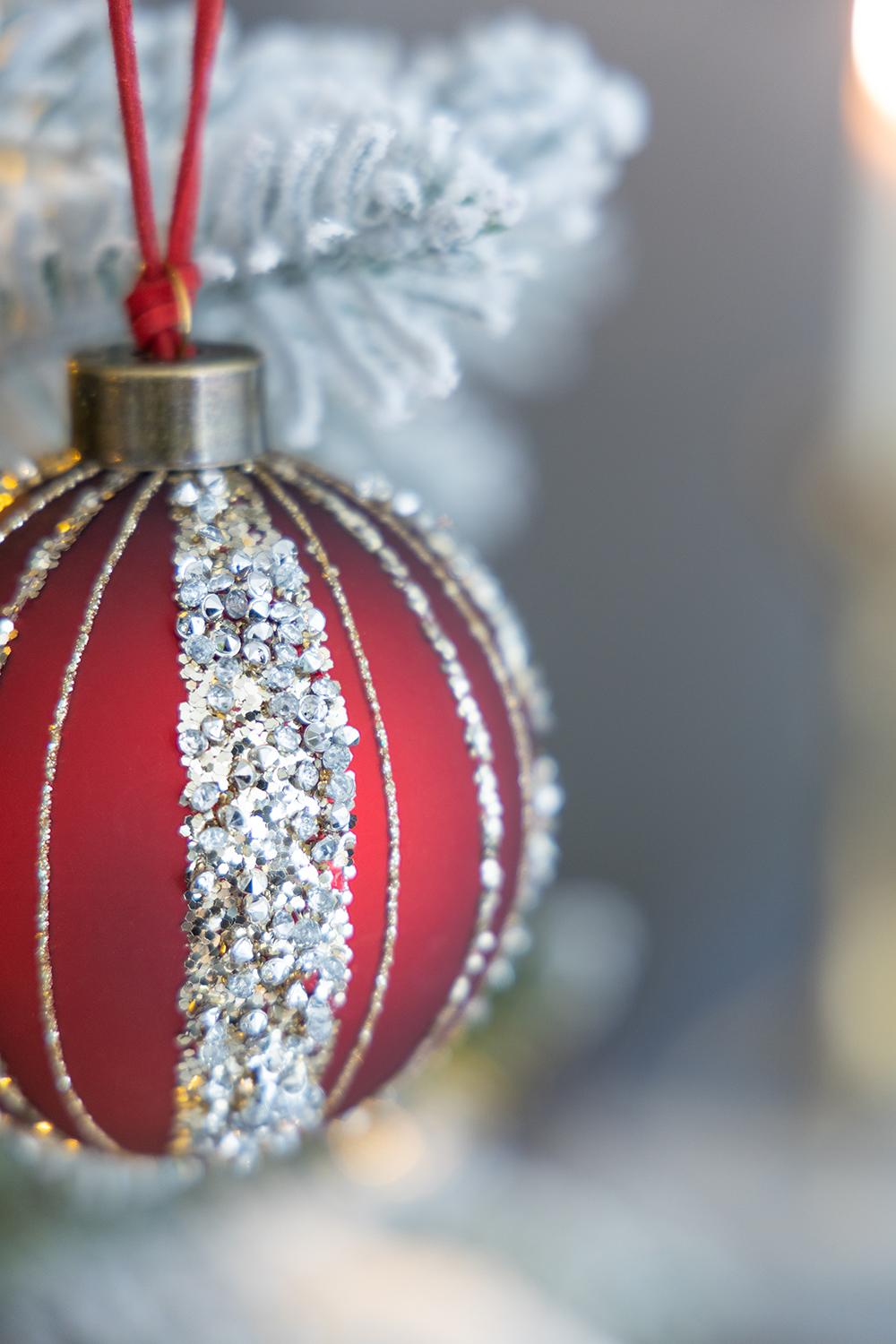 Red glass Christmas ornament with silver glitter stripes and rhinestone accents