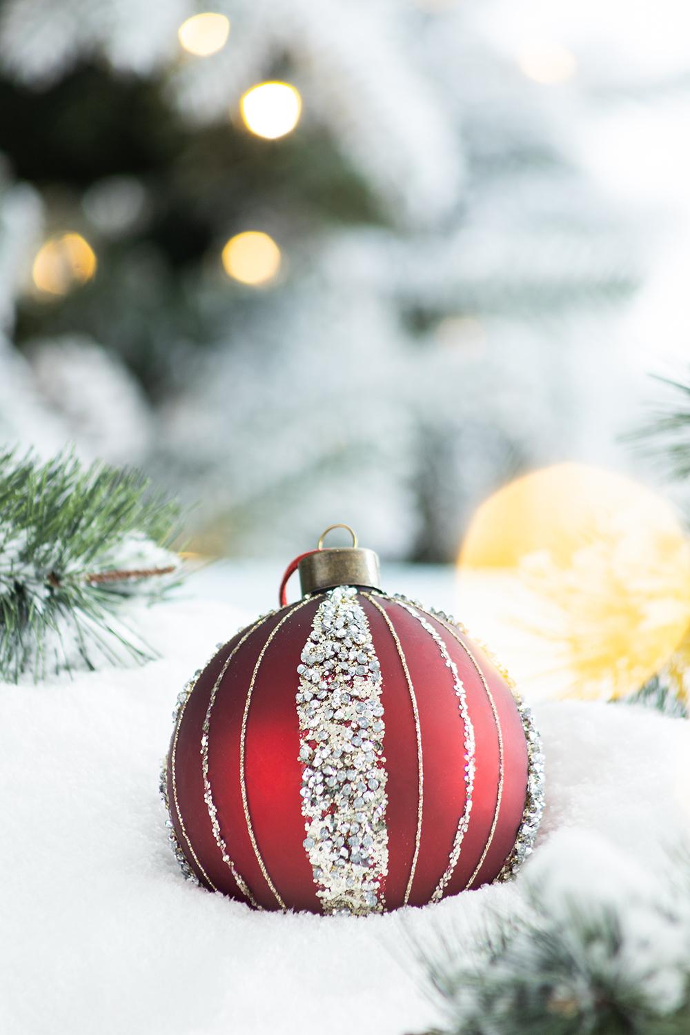 Shiny red Christmas bauble with glitter accents on faux snow
