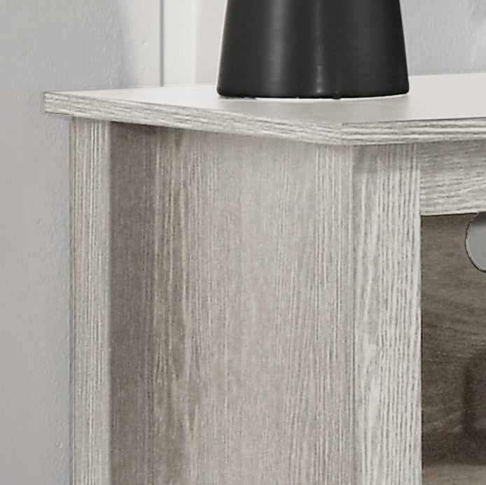 Closeup of light grey wood grain laminate on a TV stand edge