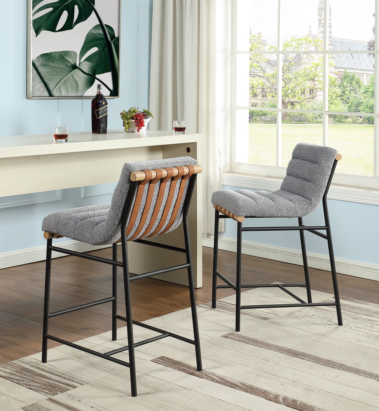 Two gray boucle bar stools with brown leather straps and natural wood accents