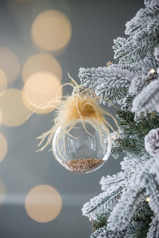 Clear glass Christmas ornament filled with gold glitter topped with beige feathers