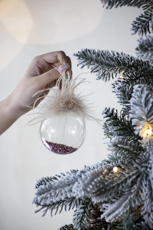 Clear glass Christmas bauble filled with purple glitter adorned with fluffy pink feathers