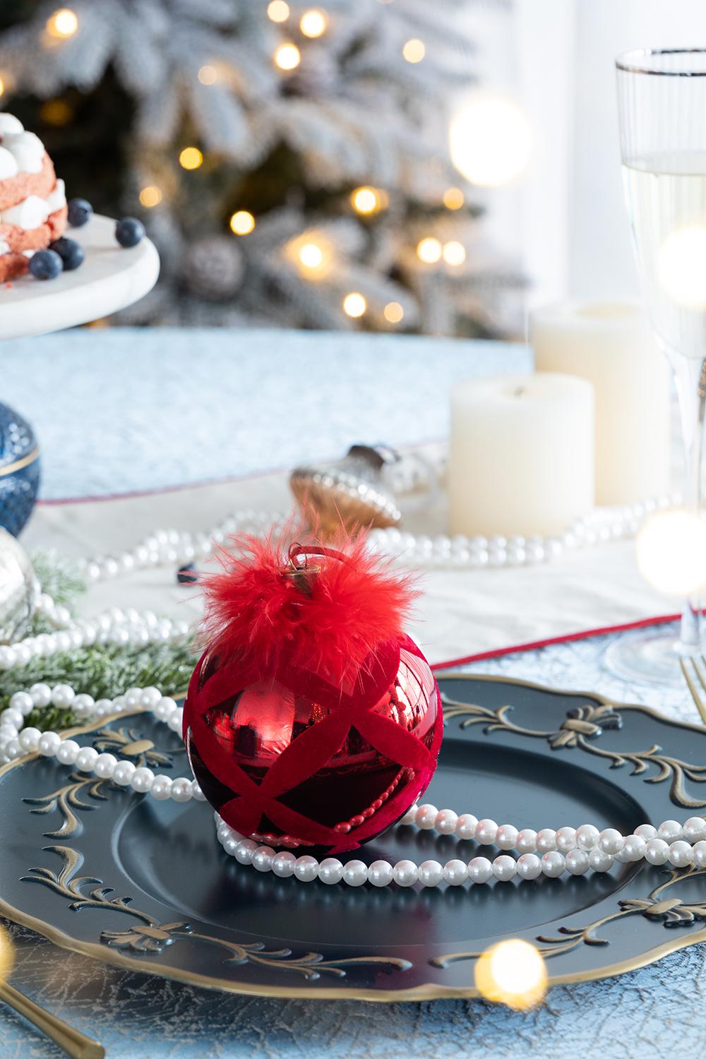 Shiny red Christmas bauble with feather accent on dark plate
