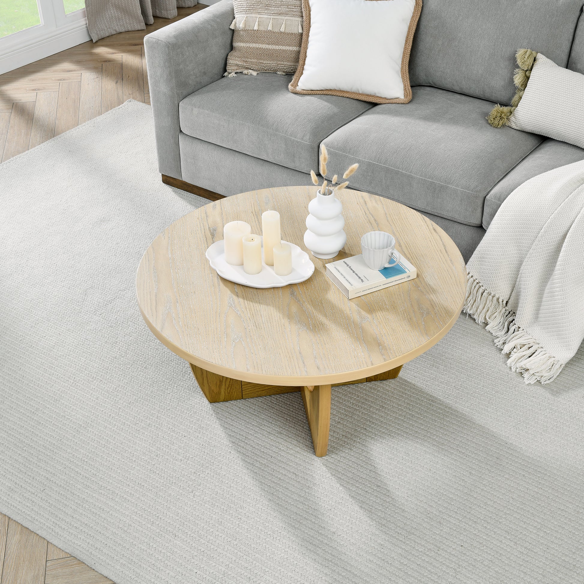 Light gray textured sofa with cream and beige decorative pillows and a white throw blanket