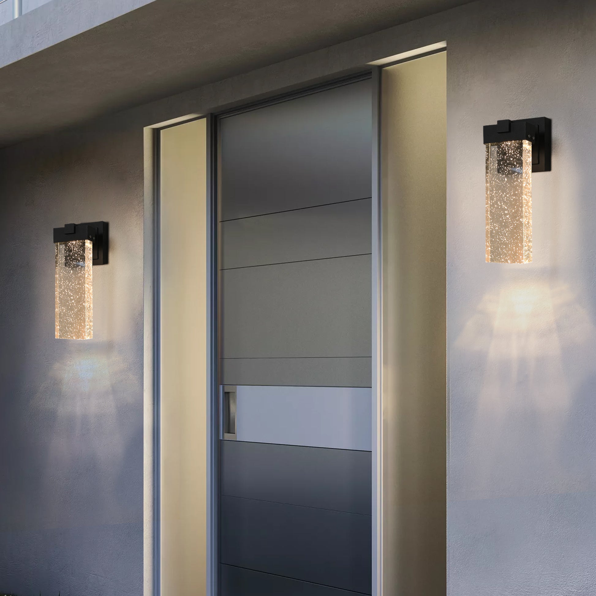 Modern black outdoor wall light with clear seeded glass cylinder illuminating entryway