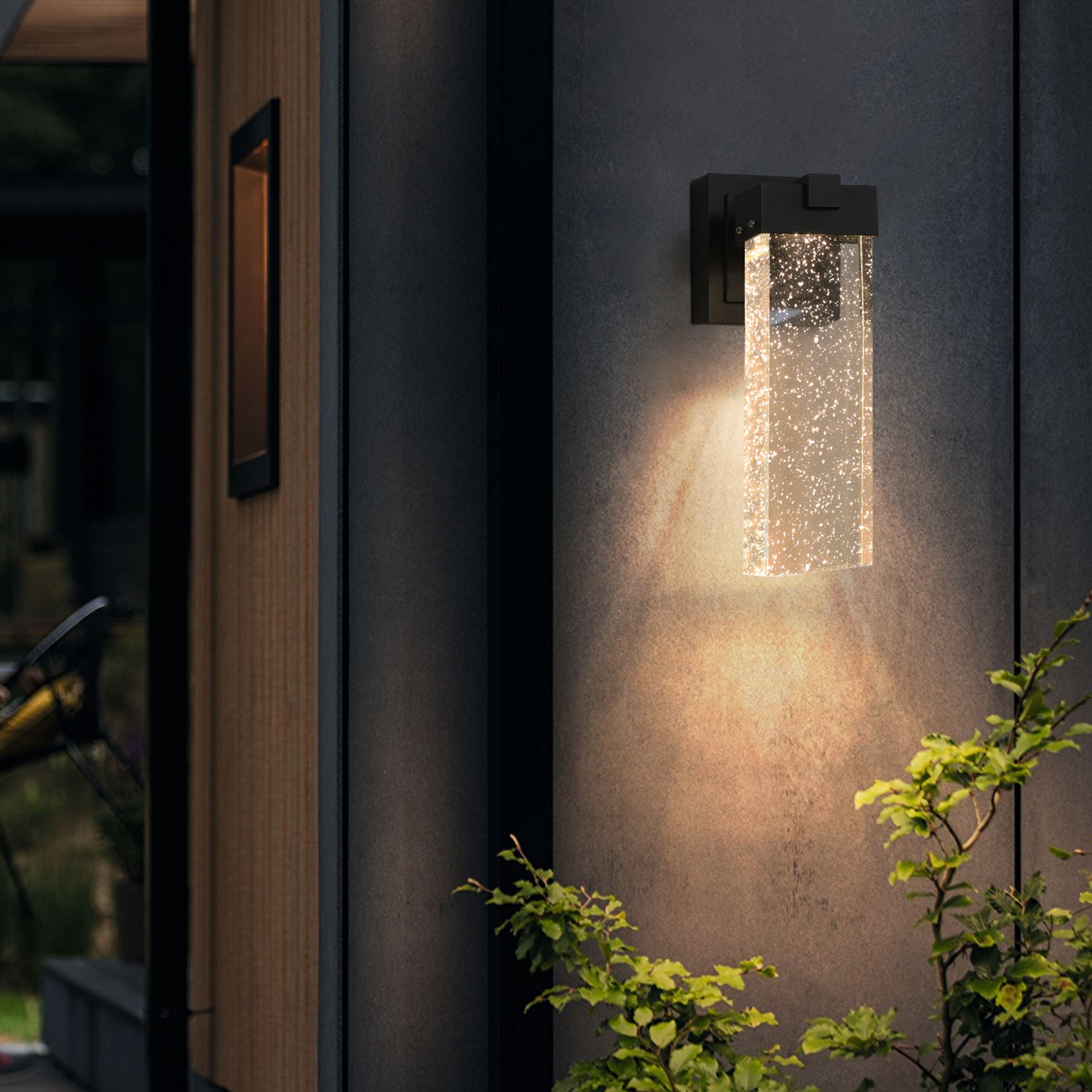 Modern black outdoor wall sconce with clear bubble glass shade and warm LED light