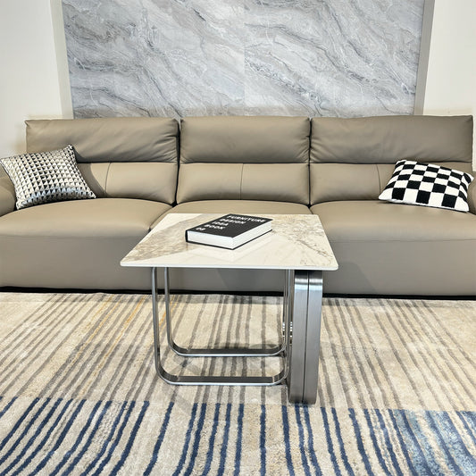 Modern light grey leather seater sofa with decorative pillows and a marbletop side table