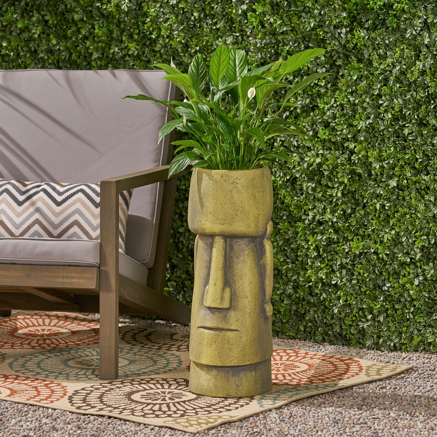 Distressed yellow resin Moai planter with green plant adds tropical flair to outdoor spaces