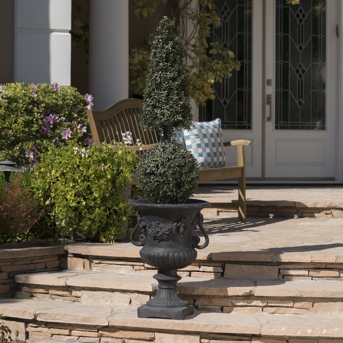 Elegant black urn with sculpted cherubs and roses featuring a conical topiary plant