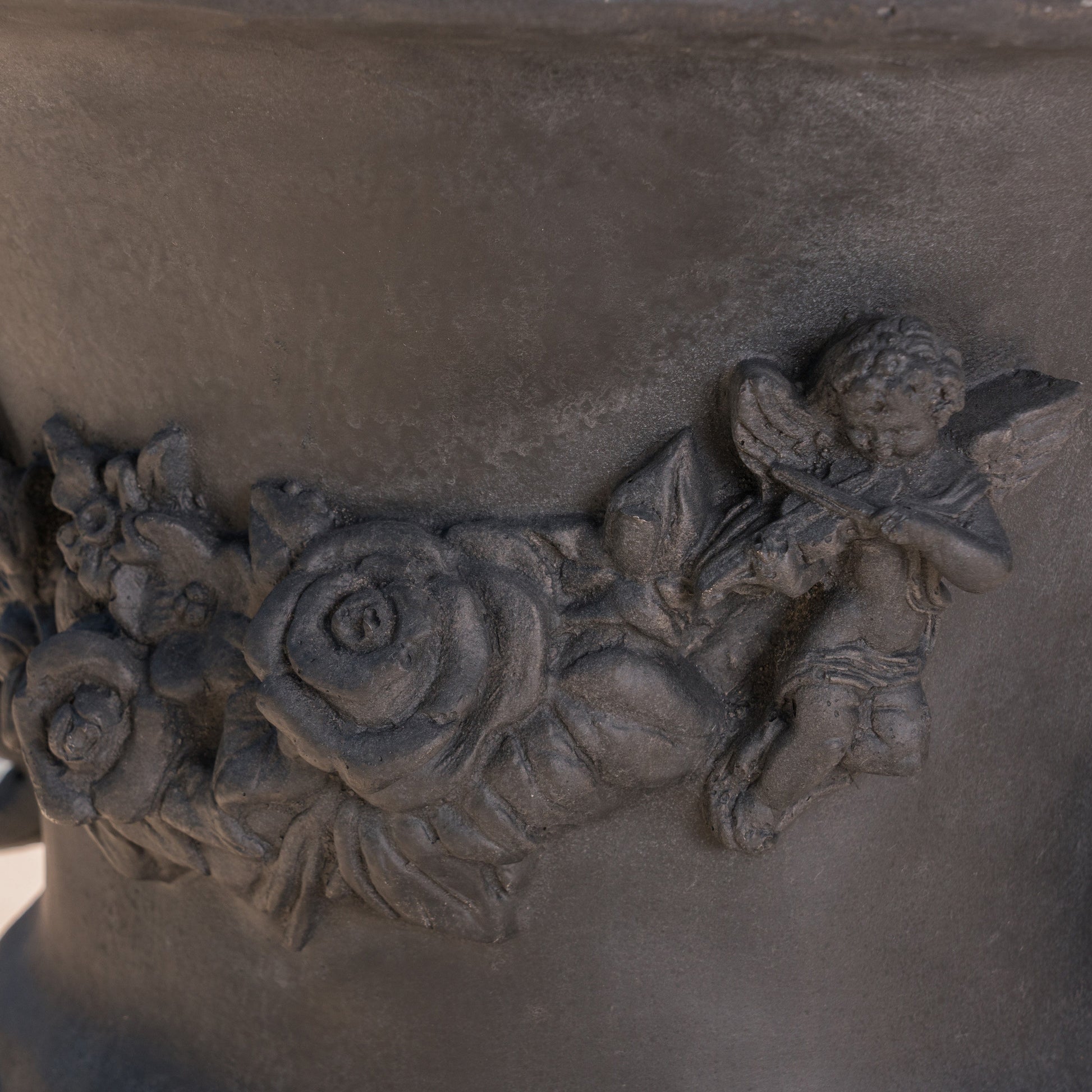 Dark grey stone planter with an ornate cherub and rose relief antique garden decor