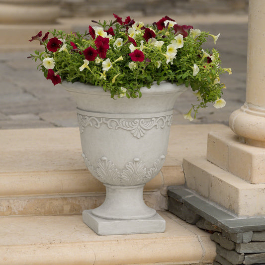 Ornate stone urn planter filled with red and white petunias perfect for garden decor