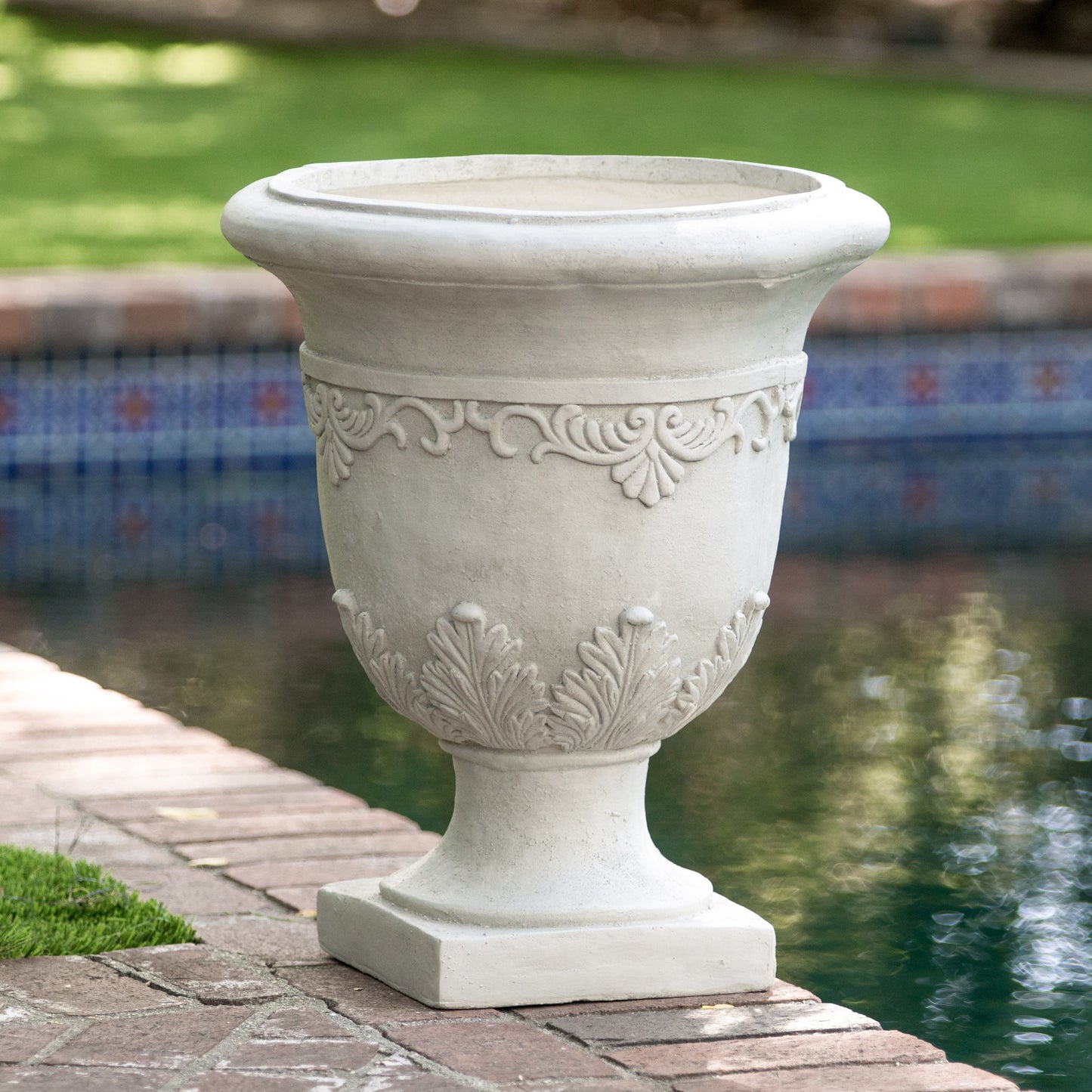 Elegant white concrete garden urn with ornate scroll and leaf detailing perfect for poolside decor