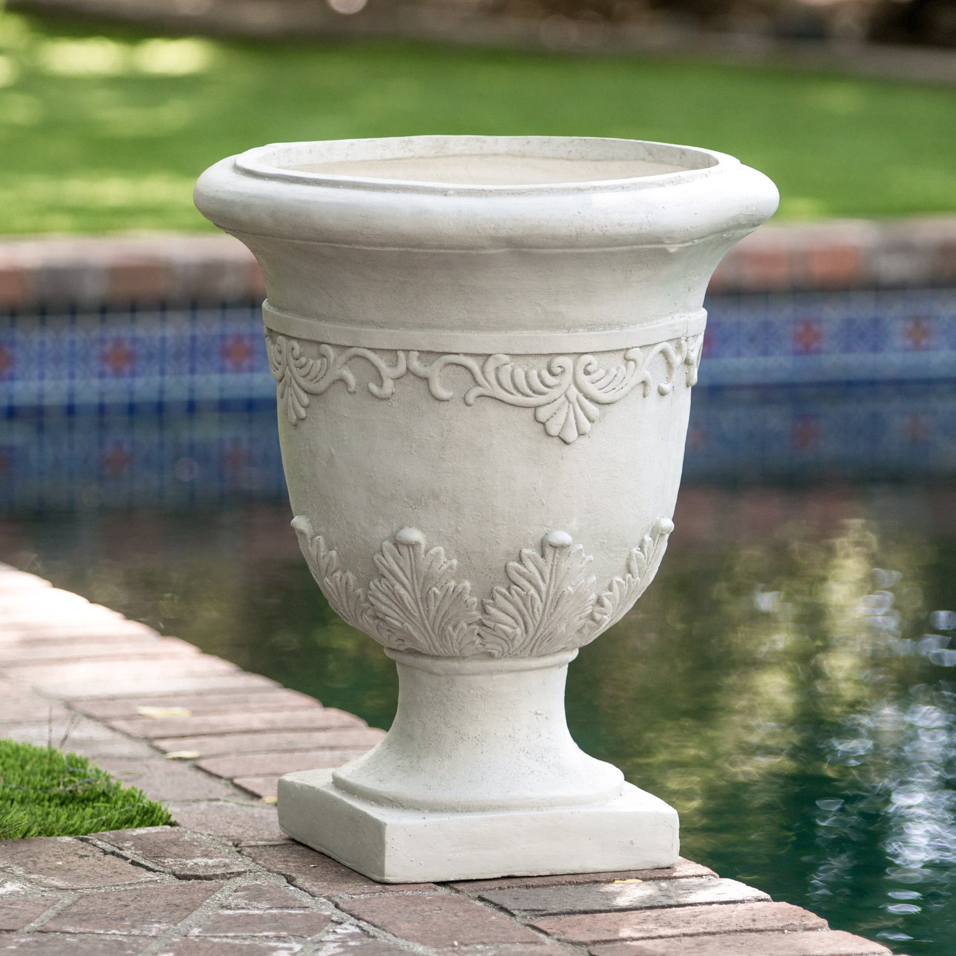 Elegant white concrete garden urn with ornate scroll and leaf detailing perfect for poolside decor
