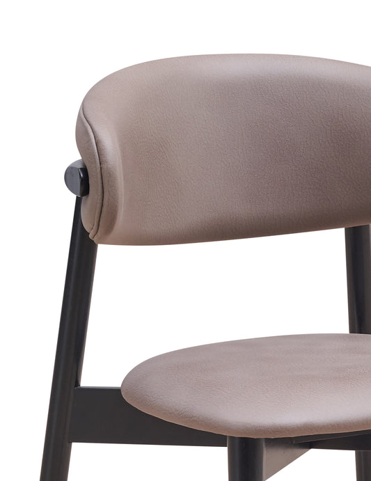 Closeup of a taupe upholstered modern accent chair with black legs