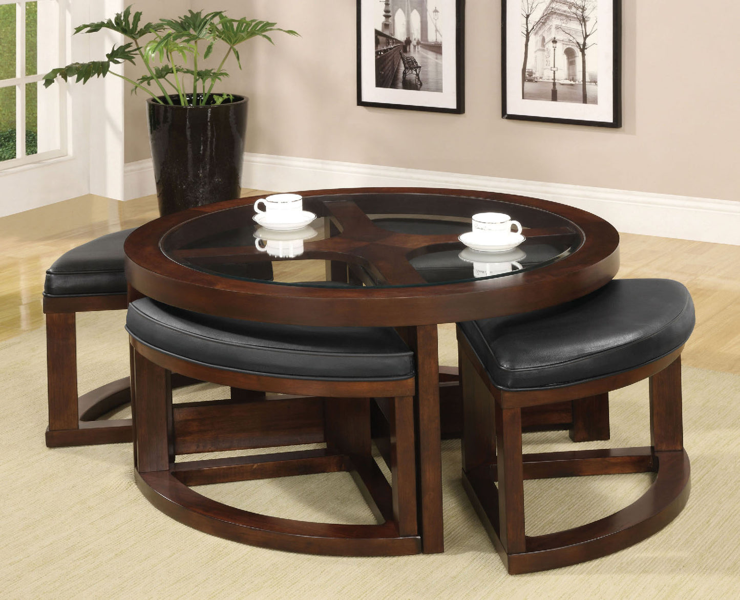 Round wooden coffee table with glass top and four black leather ottomans