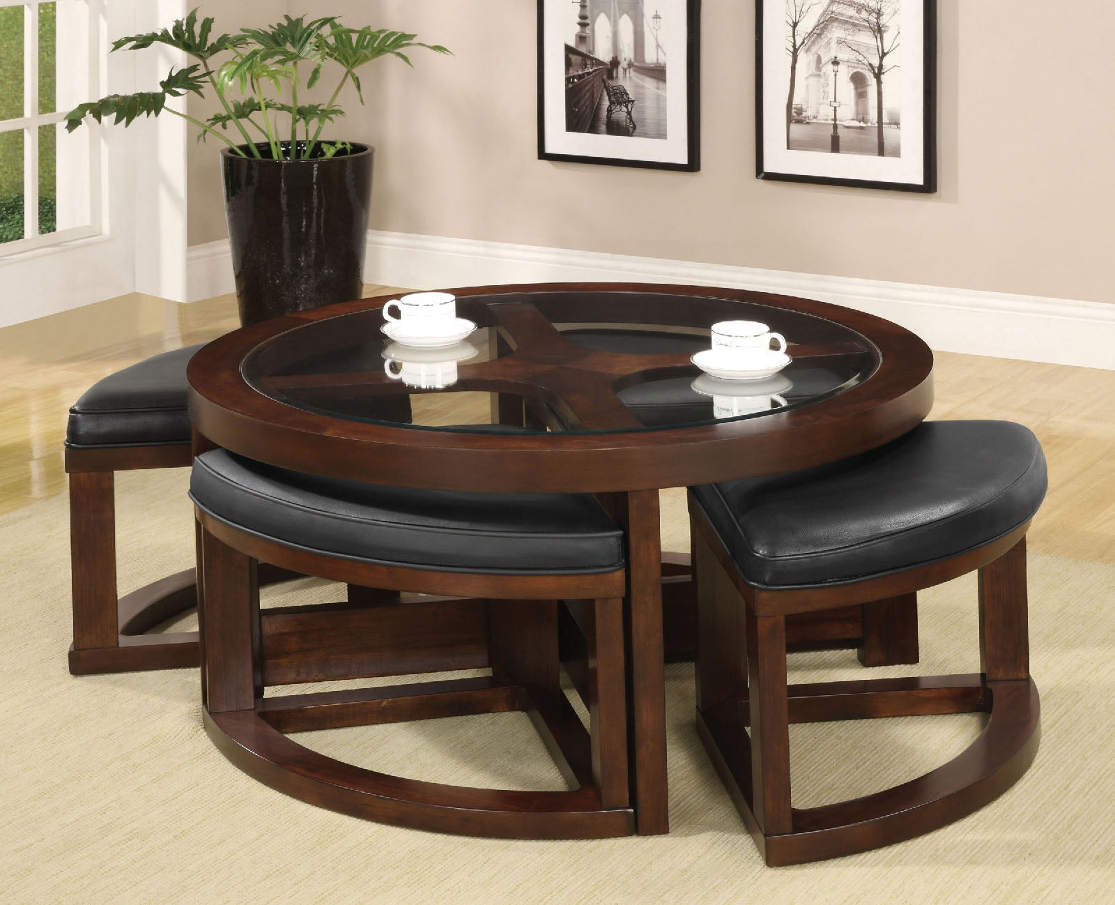 Round wooden coffee table with glass top and four black leather ottomans