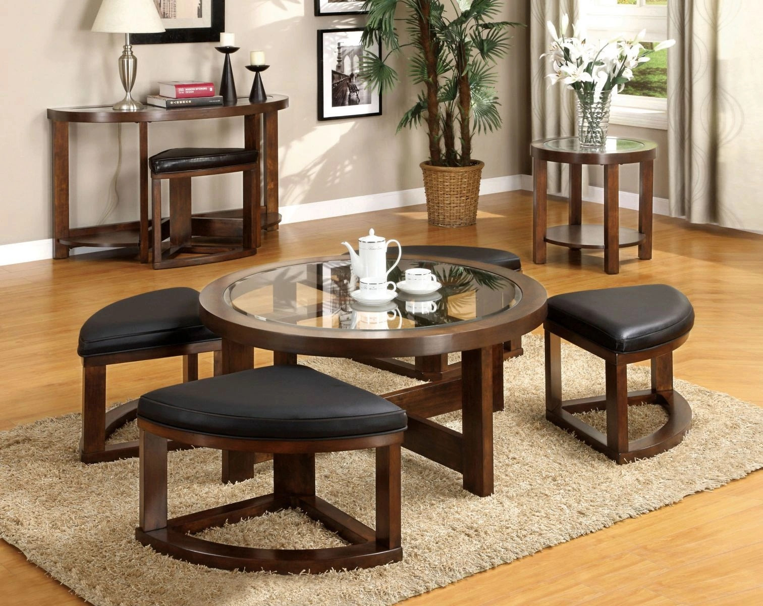 Round coffee table with glass top and dark wood frame includes four black leatherette ottomans