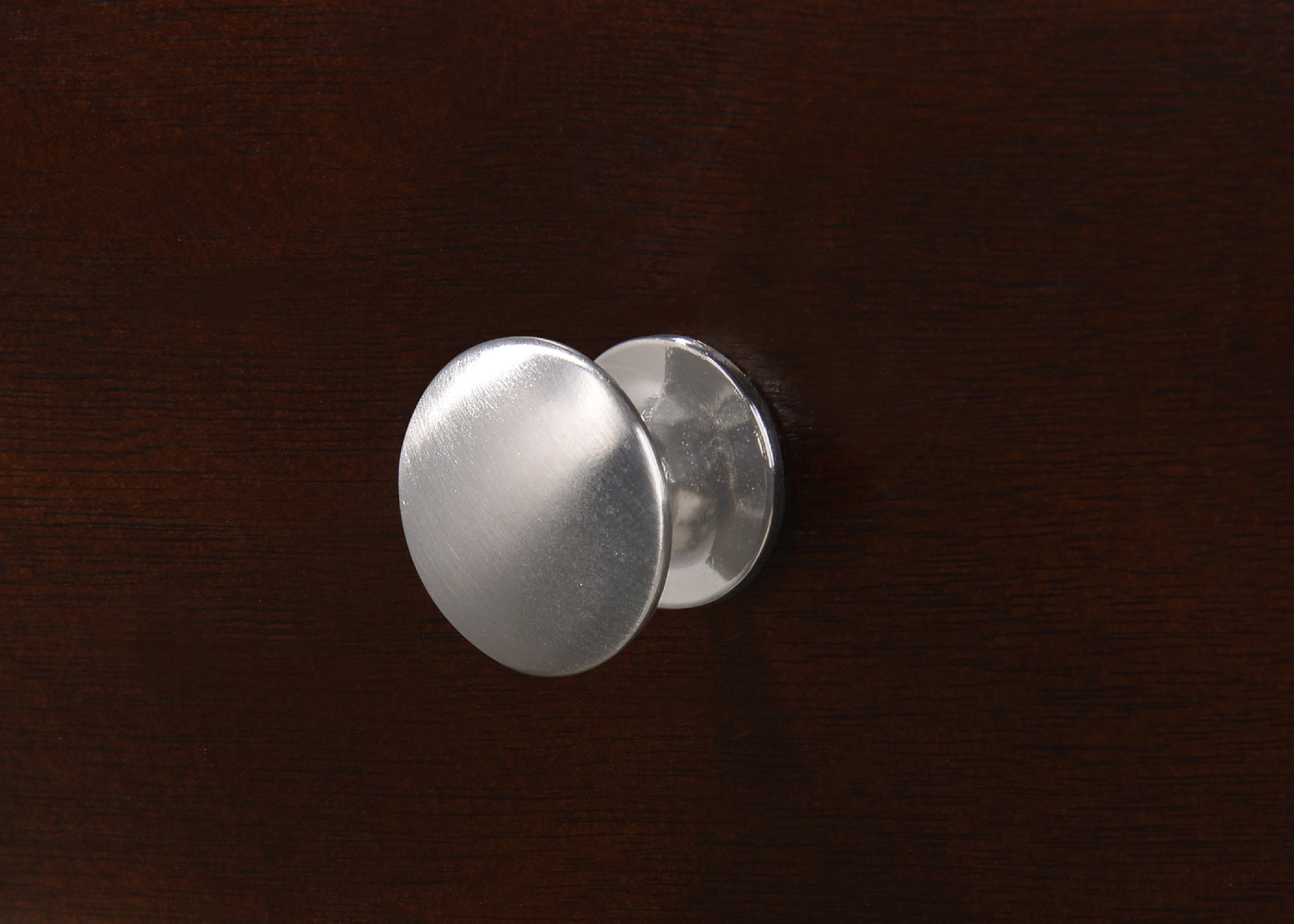 Brushed nickel cabinet knob on dark wood furniture