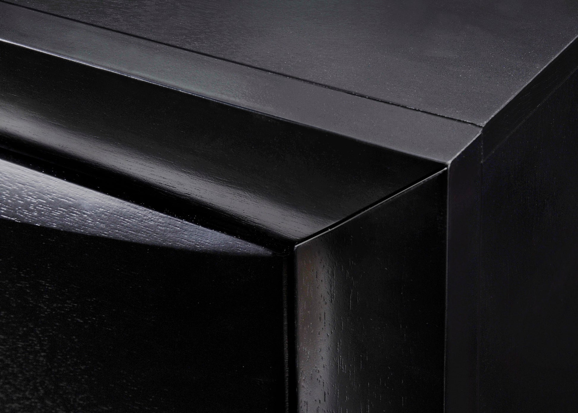 Closeup of a glossy black wooden drawer with subtle wood grain texture