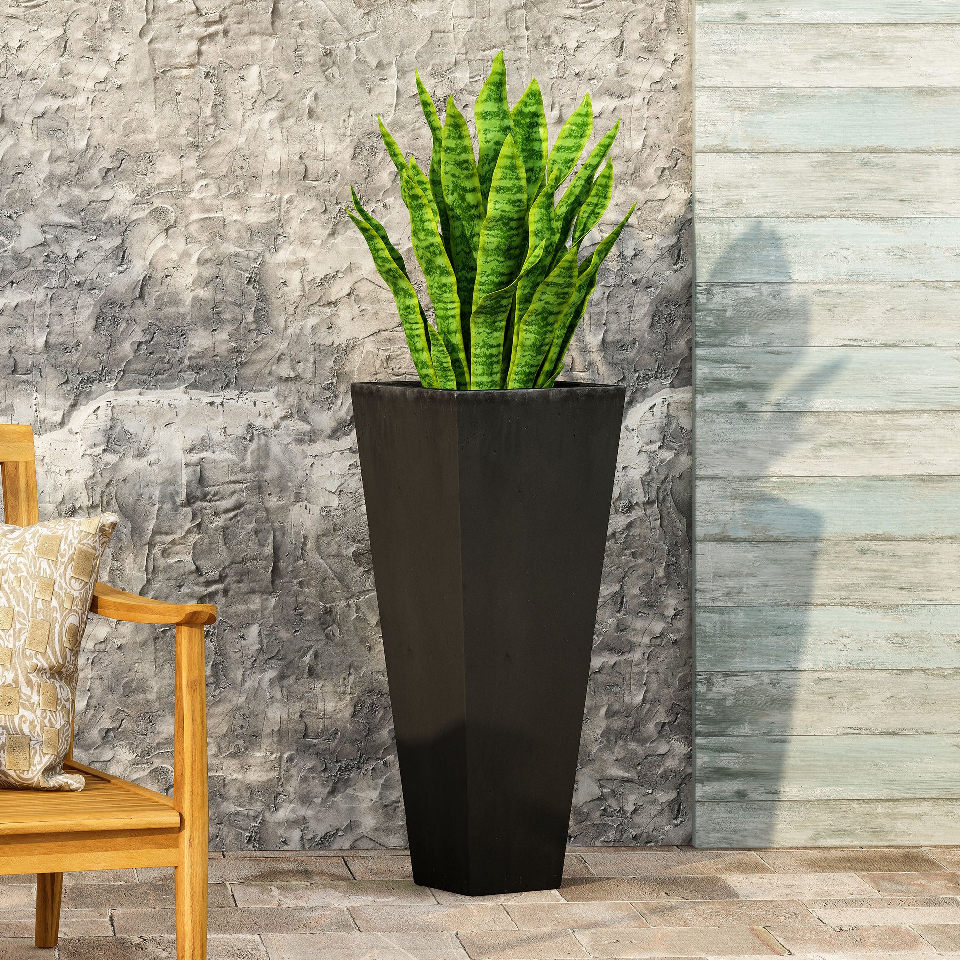 Tall black fiberglass planter with vibrant green snake plant perfect for modern outdoor decor
