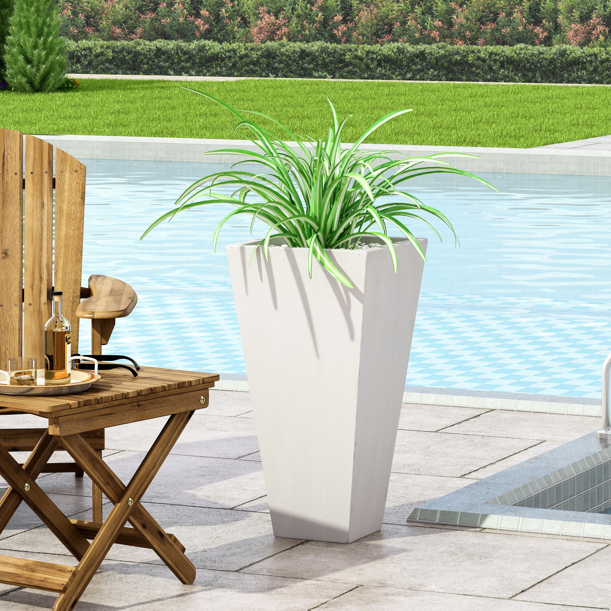 Tall tapered white planter with green and white striped spider plant by poolside