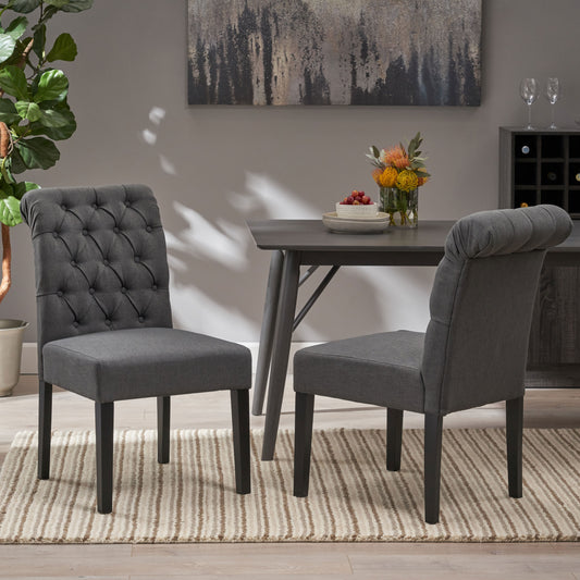 Two dark gray fabric dining chairs with tufted backs and wooden legs
