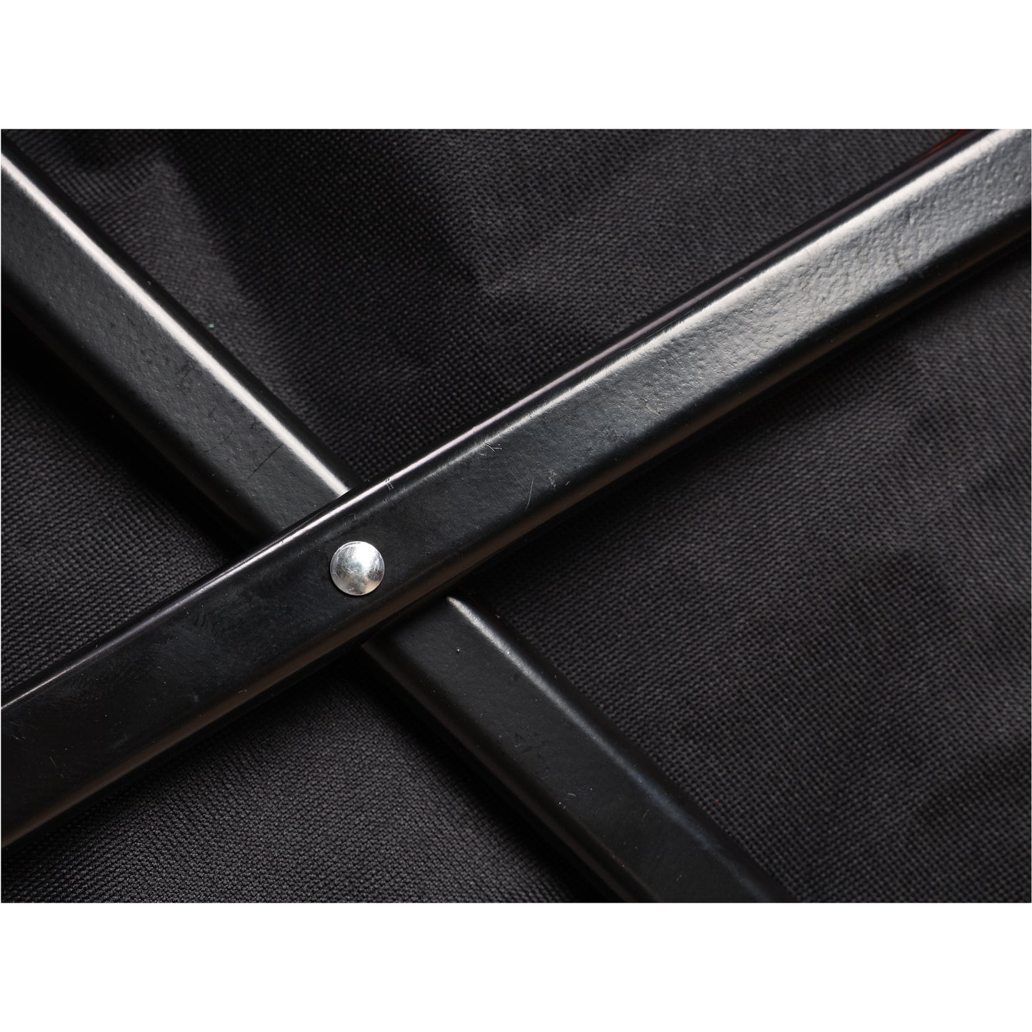 Closeup of black metal frame with silver rivet on woven fabric