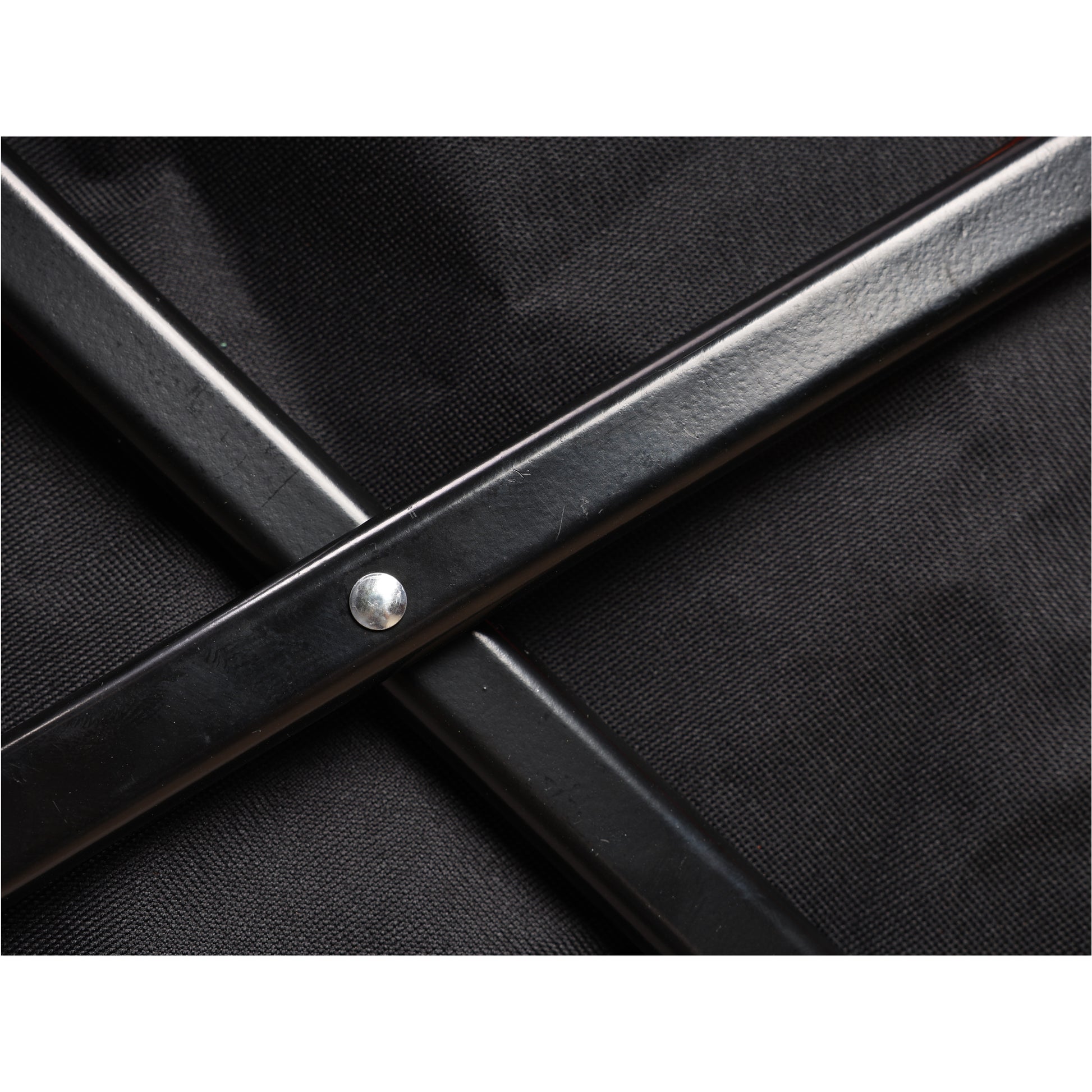 Closeup of black metal frame with silver rivet on woven fabric